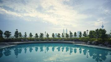 Una piscina al aire libre, sombrillas, sillones reclinables de piscina