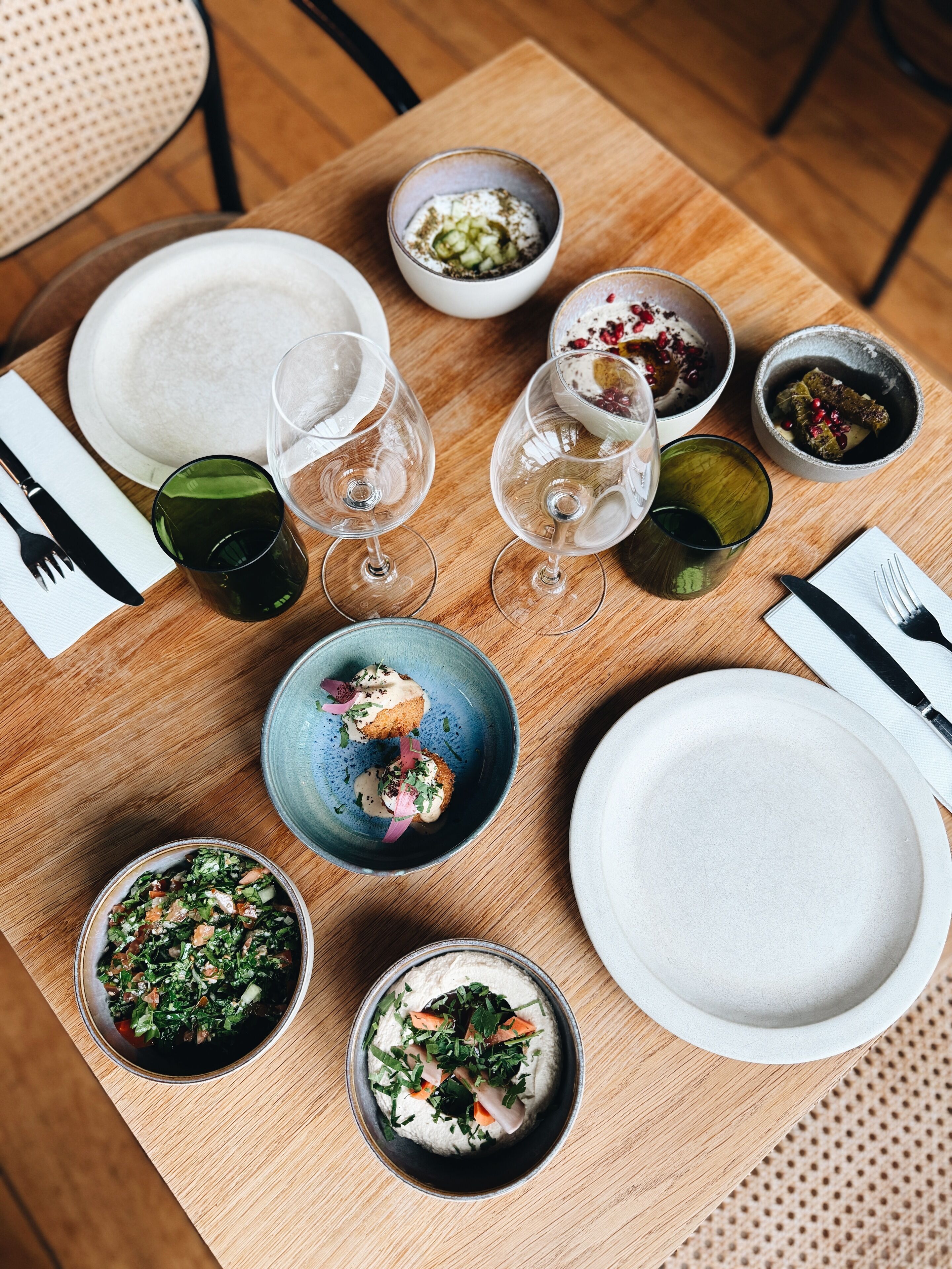 A dining table with various dishes, glasses, and cutlery.
