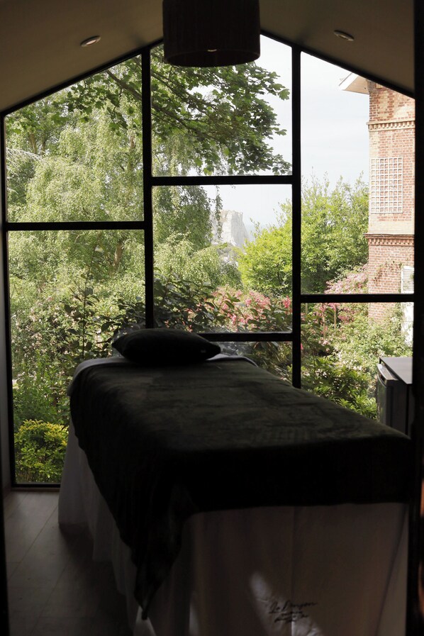 Ein Zimmer mit großem Fenster, einem Bett und einer Ziegelwand.