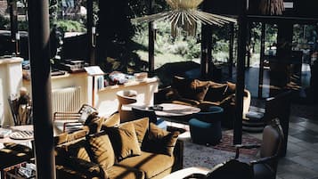 Un salon moderne avec un canapé, des fauteuils et une table basse. Une fenêtre offre une vue sur l’extérieur.
