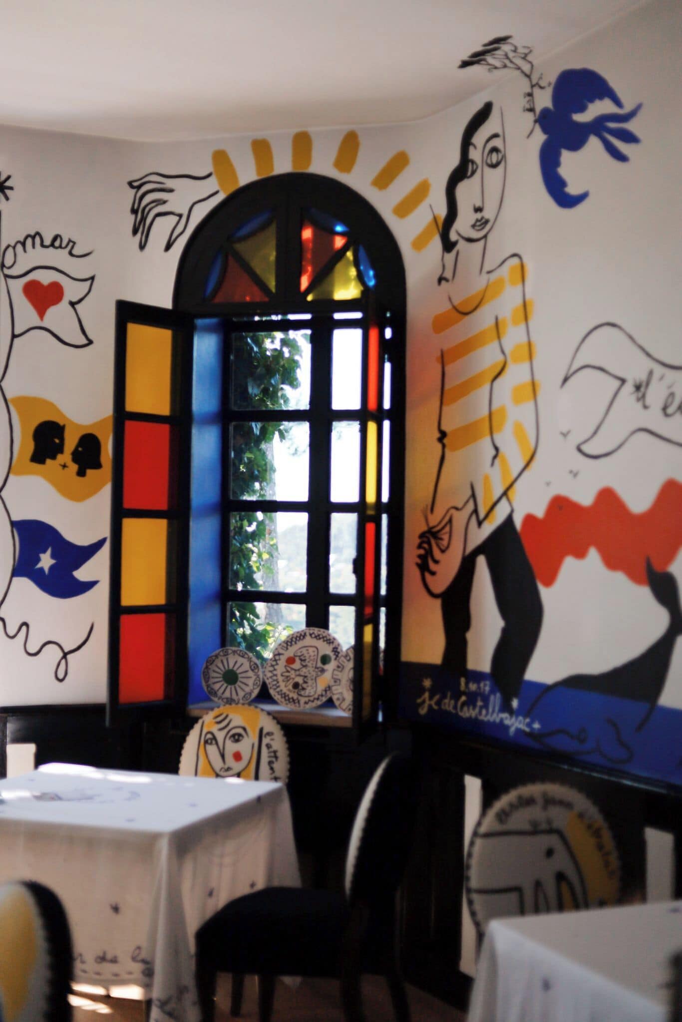 A dining area with a table, chairs, and a window with colorful stained glass.