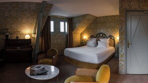 Une chambre d’hôtel avec un lit, un bureau, une chaise, une petite table et une porte.