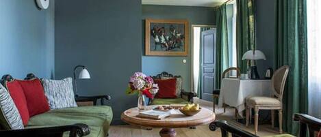 A living room with a green sofa, a round wooden coffee table, and a painting on the wall.