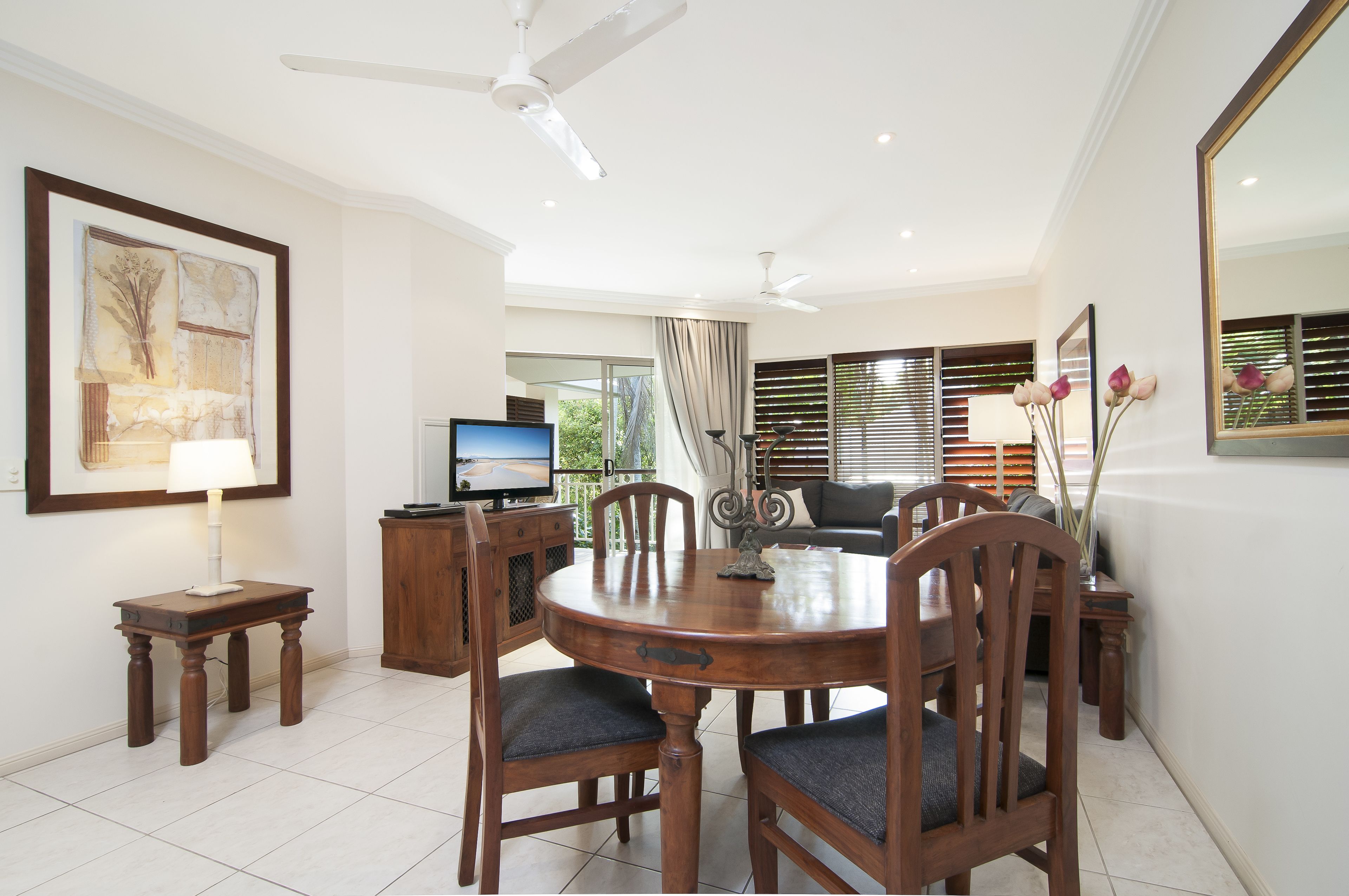 A dining area with a wooden table and chairs, a television, and a framed artwork on the wall.