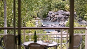 A patio with a table and chairs, overlooking a garden with a waterfall and rocks. - Paradise Links Resort Port Douglas (Craiglie)