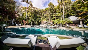 A pool area with lounge chairs, a rocky island, and tropical vegetation. - Paradise Links Resort Port Douglas (Craiglie)