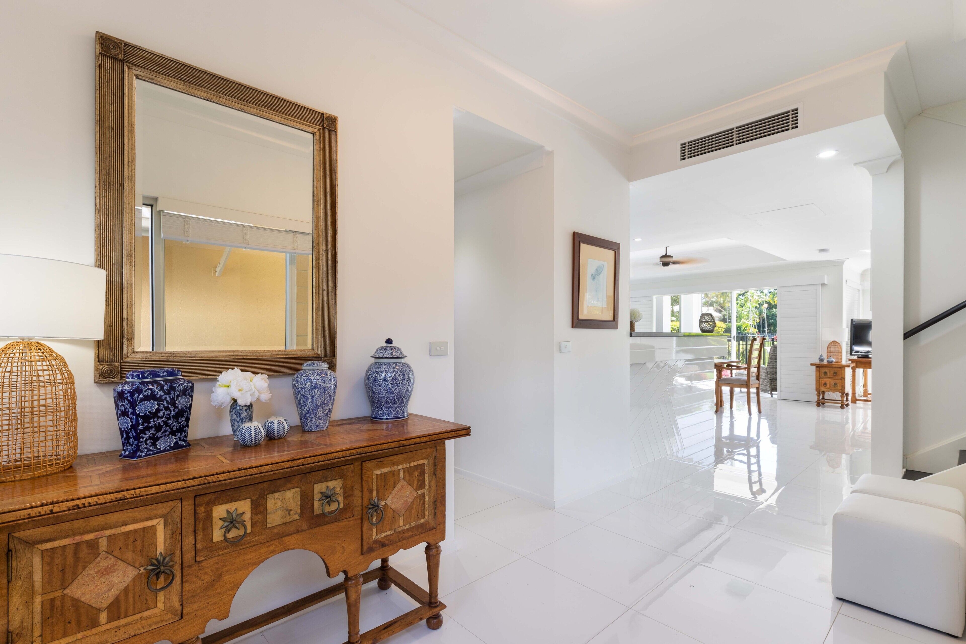 A spacious living area with a wooden console table, decorative vases, and a large mirror.
