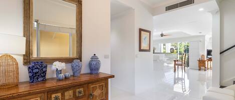 A spacious living area with a wooden console table, decorative vases, and a large mirror.