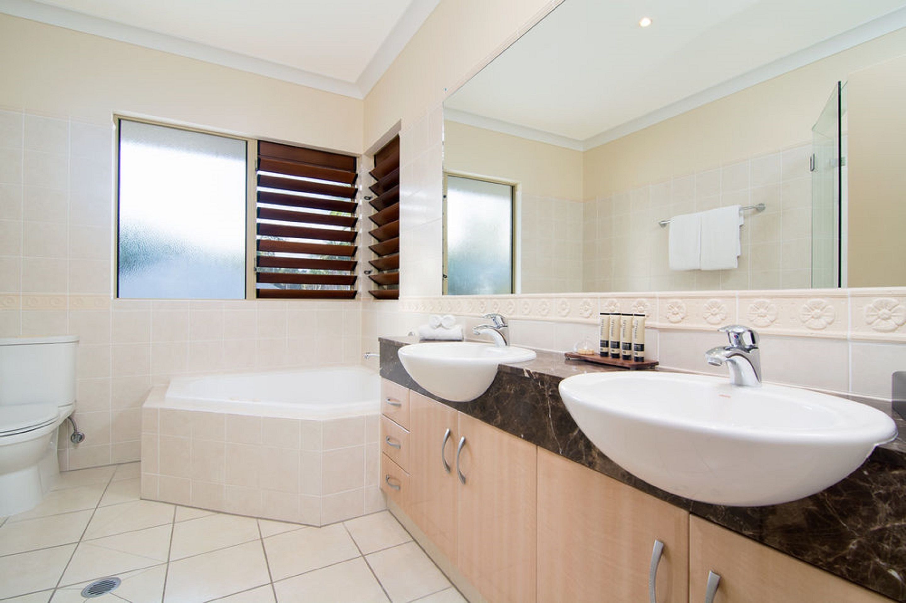Ein modernes Badezimmer mit zwei Waschbecken, einer Badewanne und einem großen Spiegel.