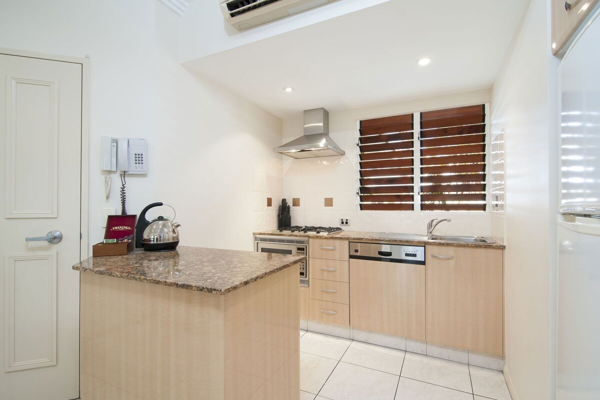A compact kitchen with a granite countertop, stainless steel appliances, and wooden cabinets.