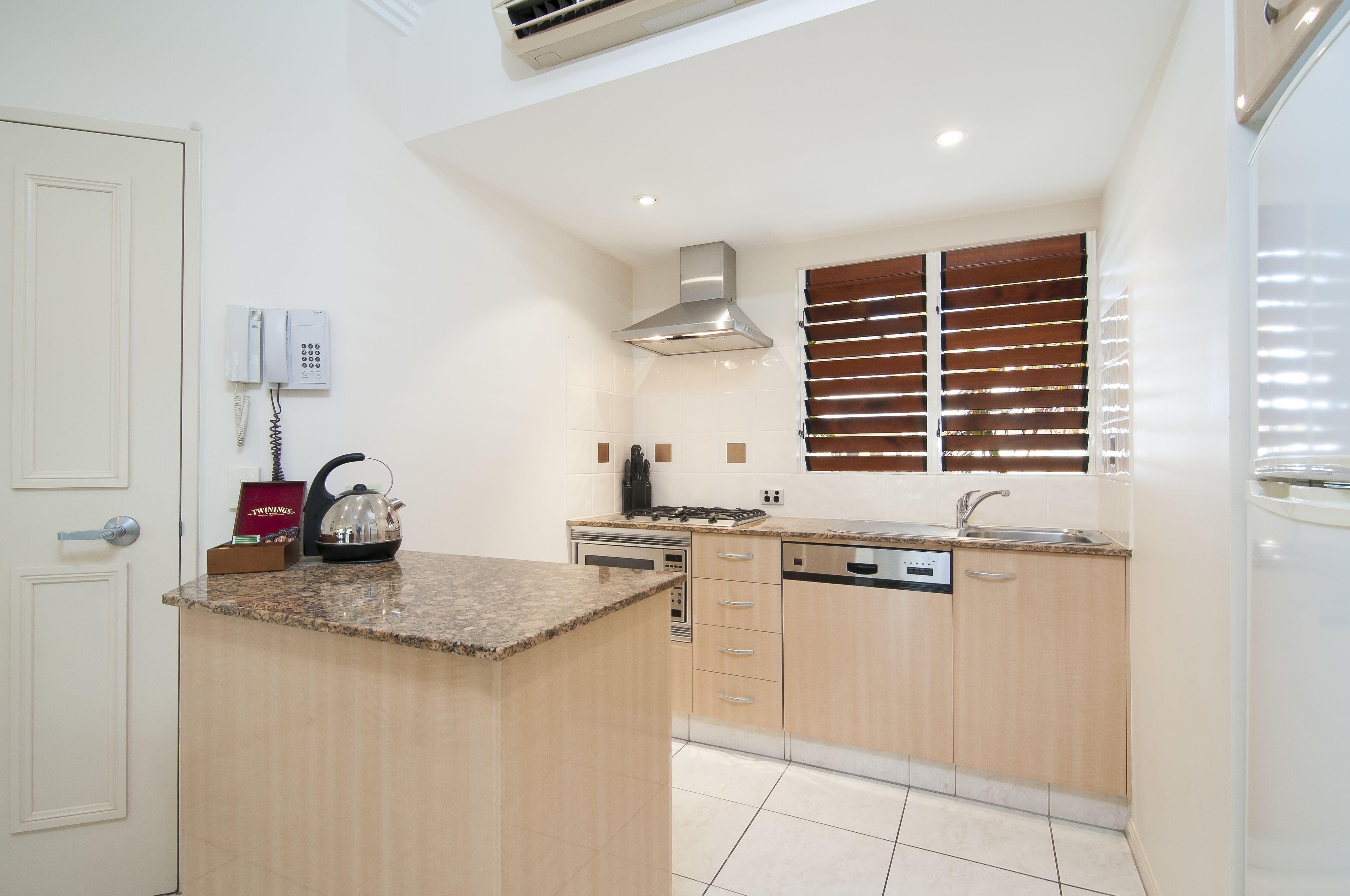 A modern kitchen with a granite countertop, stainless steel appliances, and wooden cabinets.