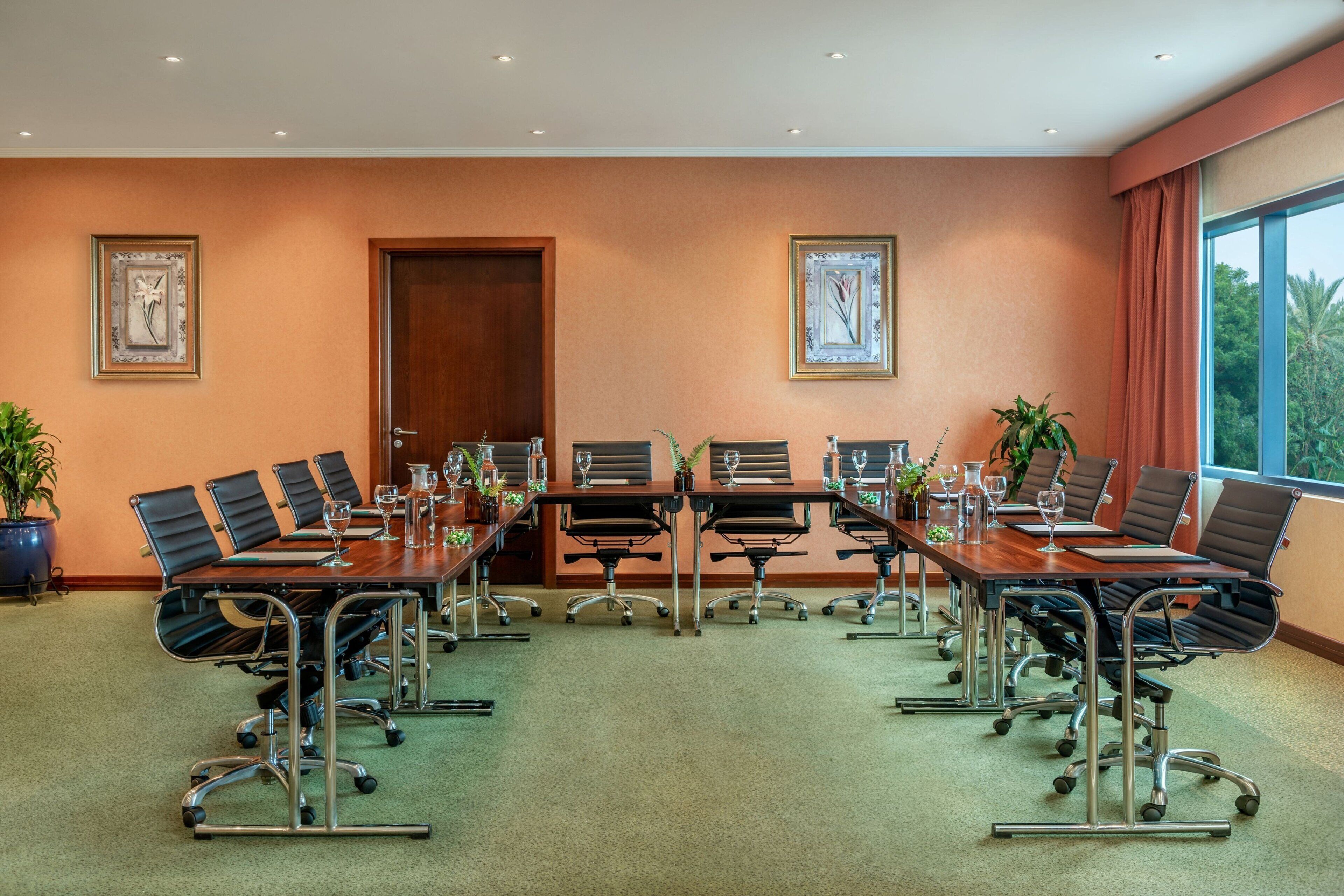 A conference room with a long table, multiple chairs, and framed artwork on the walls.