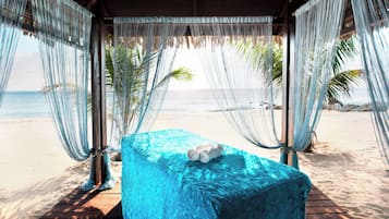 Relax in a shaded hammock under a thatched roof, overlooking the ocean.