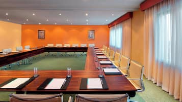 A conference room with a long table, chairs, and a green carpet.