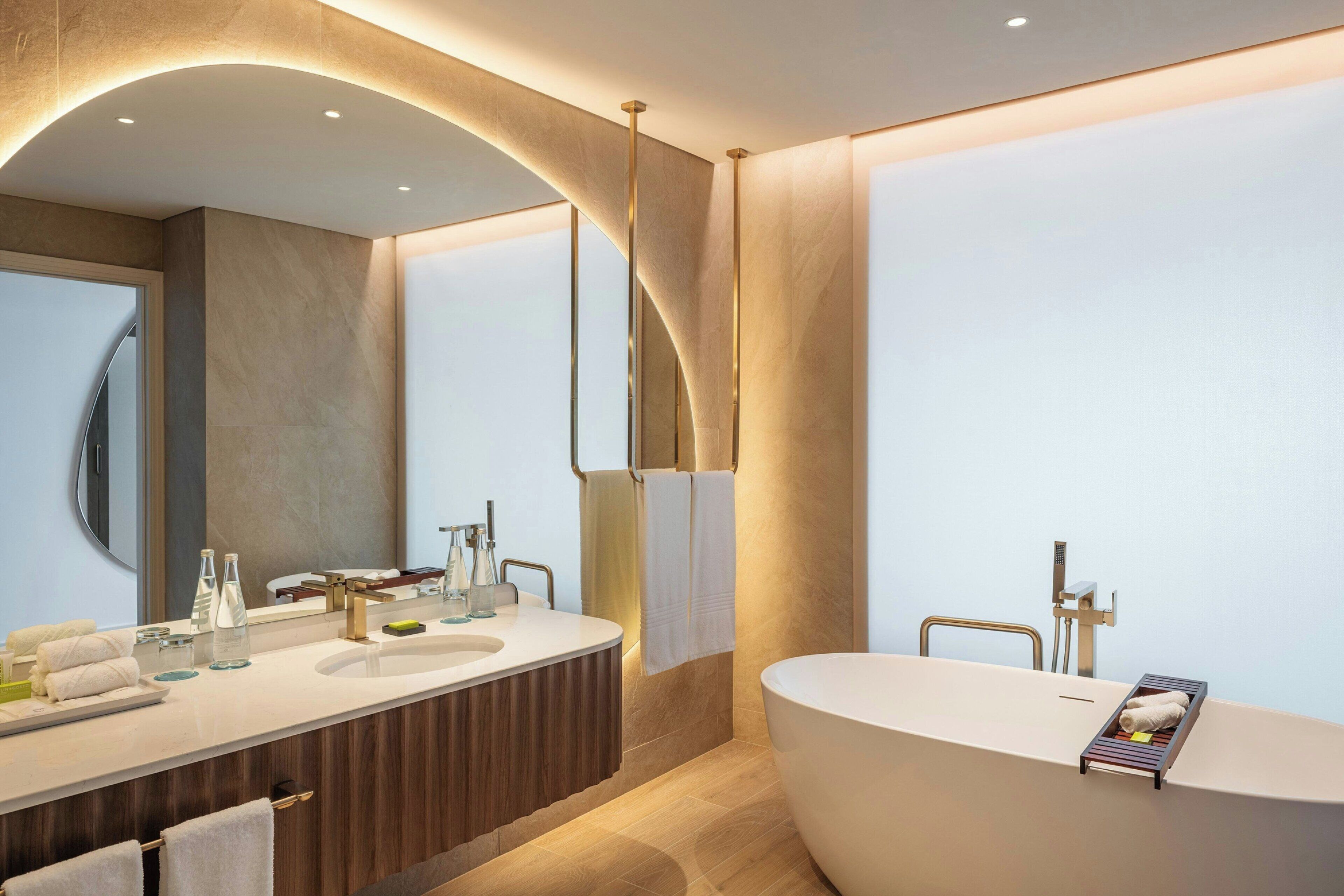 Une salle de bain moderne avec une baignoire sur pieds, un meuble-lavabo avec un miroir et un porte-serviettes.