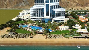 A resort with multiple swimming pools, a beach, and a large hotel building.