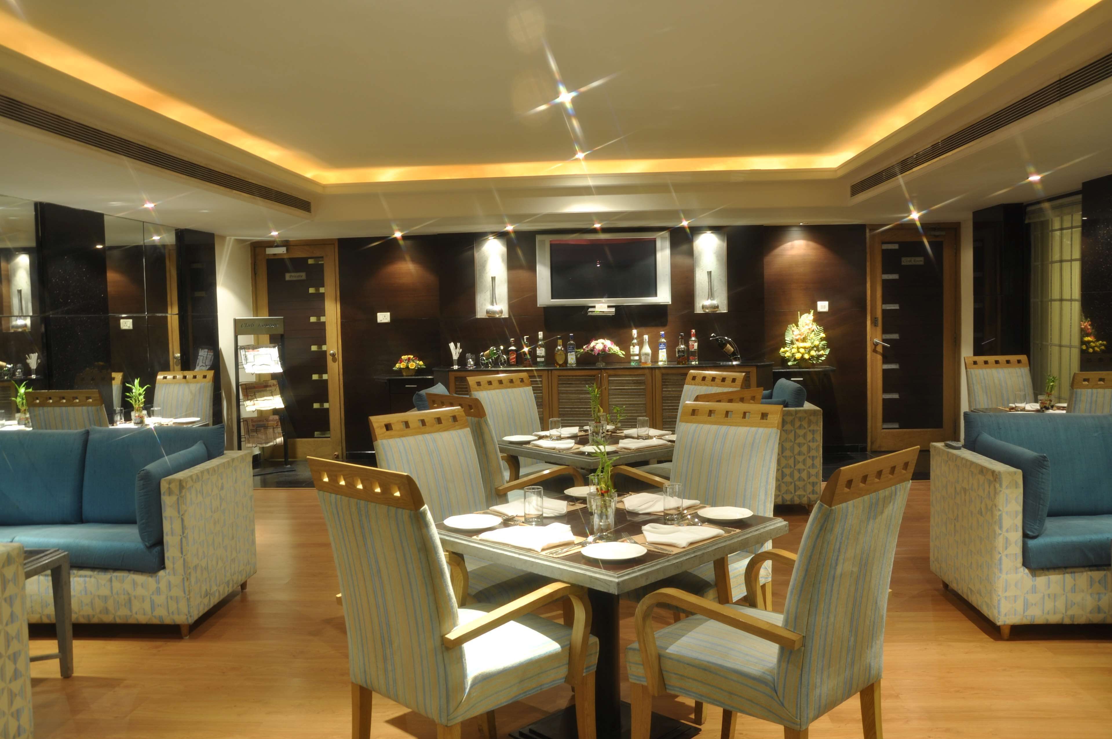 A dining area with a round table, chairs, and a bar with bottles.
