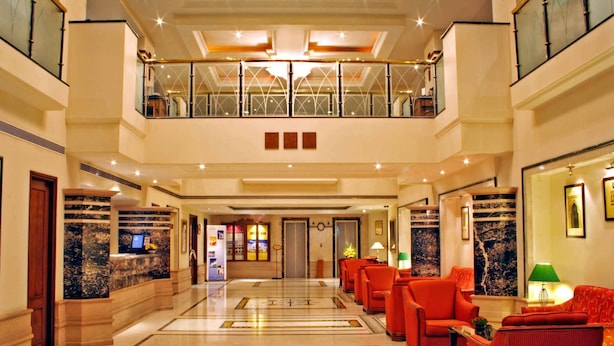 A spacious lobby with a high ceiling, a central seating area with red chairs, and a decorative floor pattern. - Aditya Park Hyderabad (Hyderabad)