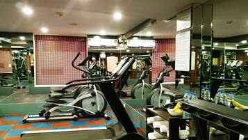 A gym with exercise equipment, mirrors, and a tiled floor.