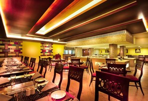 Ein Restaurant mit langen Gemeinschaftstischen, einzelnen Sitzecken und einer Bar.
