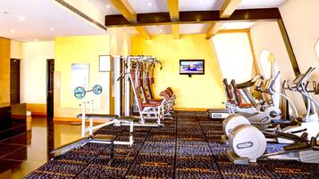Un gimnasio con varios equipos de ejercicio, un televisor en la pared y un piso con diseño.