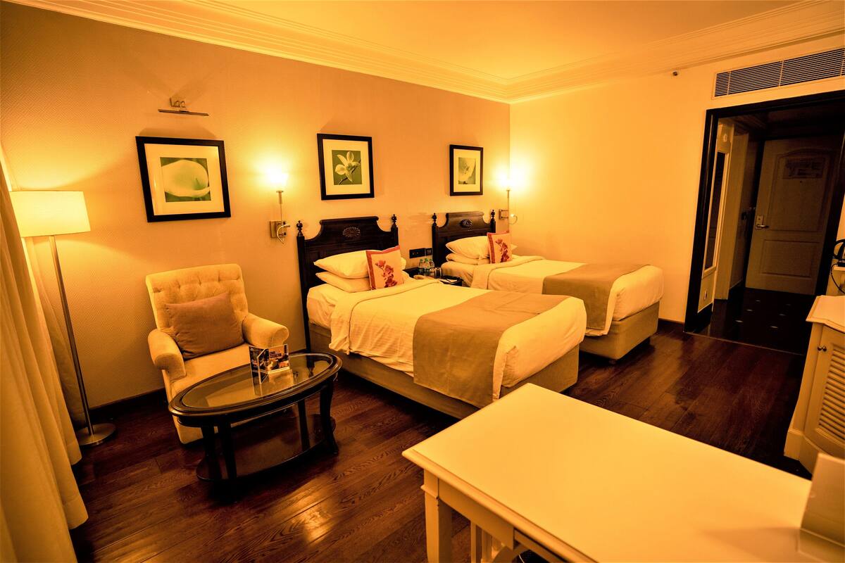 Een hotelkamer met twee bedden, een stoel, een tafel en wanddecoraties.