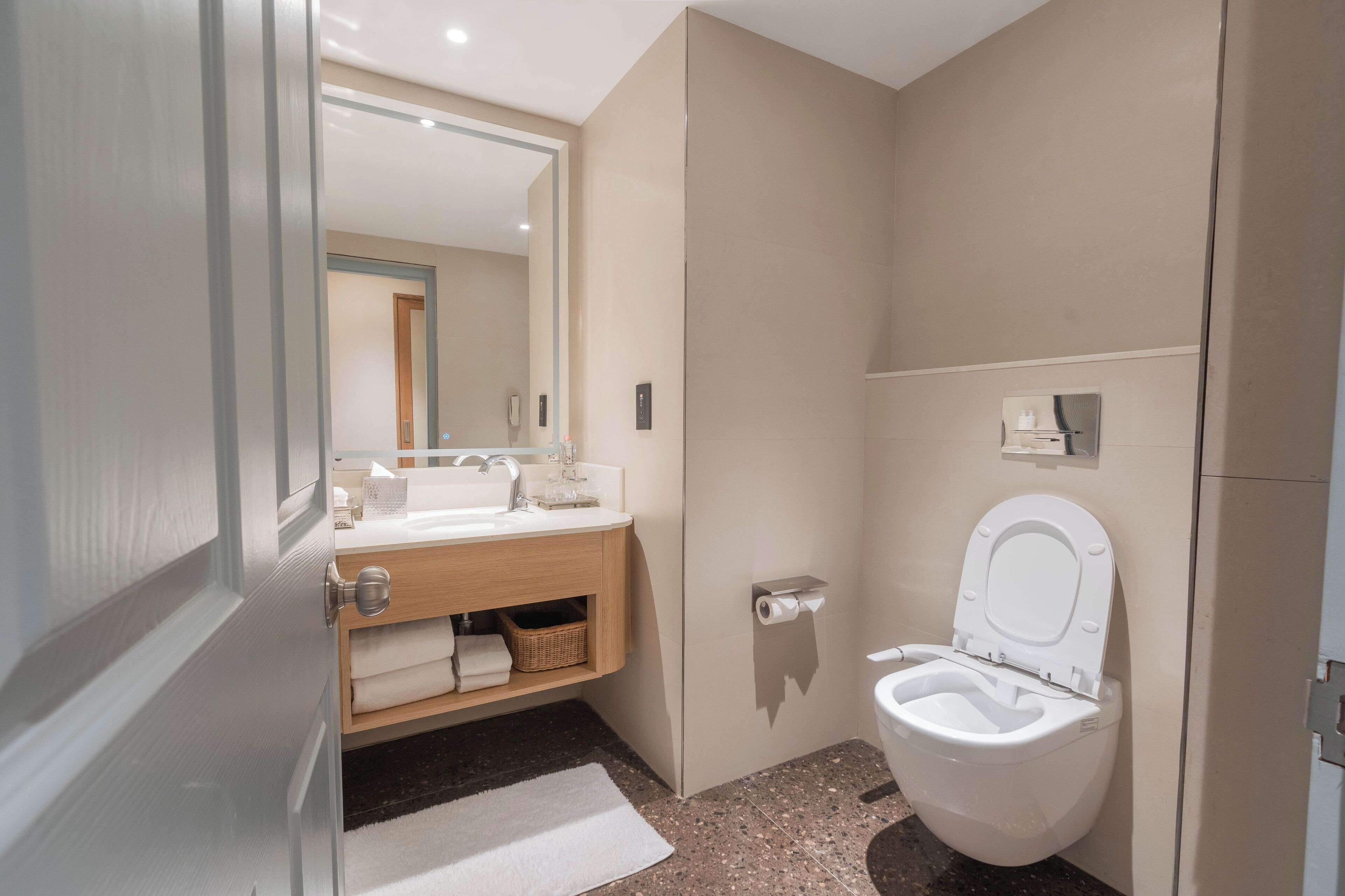 Un bagno moderno con toilette, lavandino e specchio.