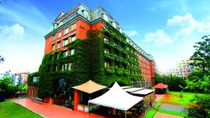 Ein mehrstöckiges Gebäude mit roter Fassade und grüner Efeu-Bewachsung an den Außenwänden.