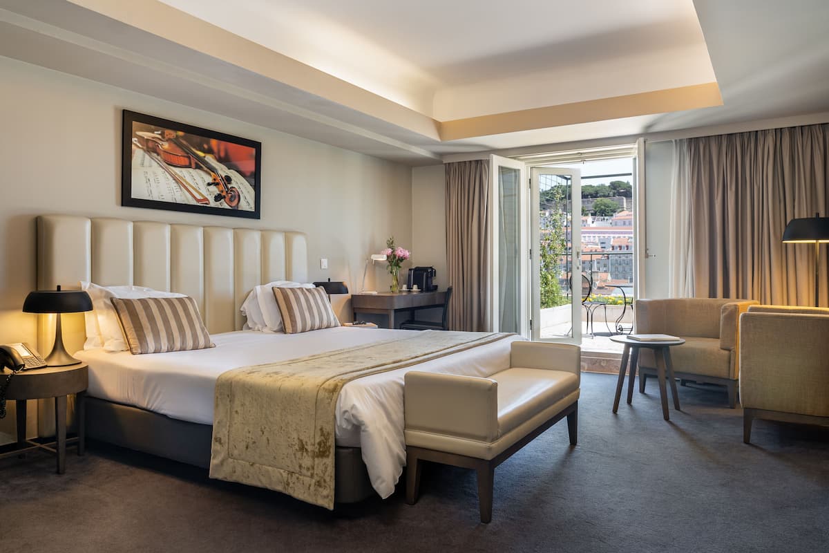 Habitación de hotel con una cama grande, un escritorio, una silla y vistas a la ciudad.