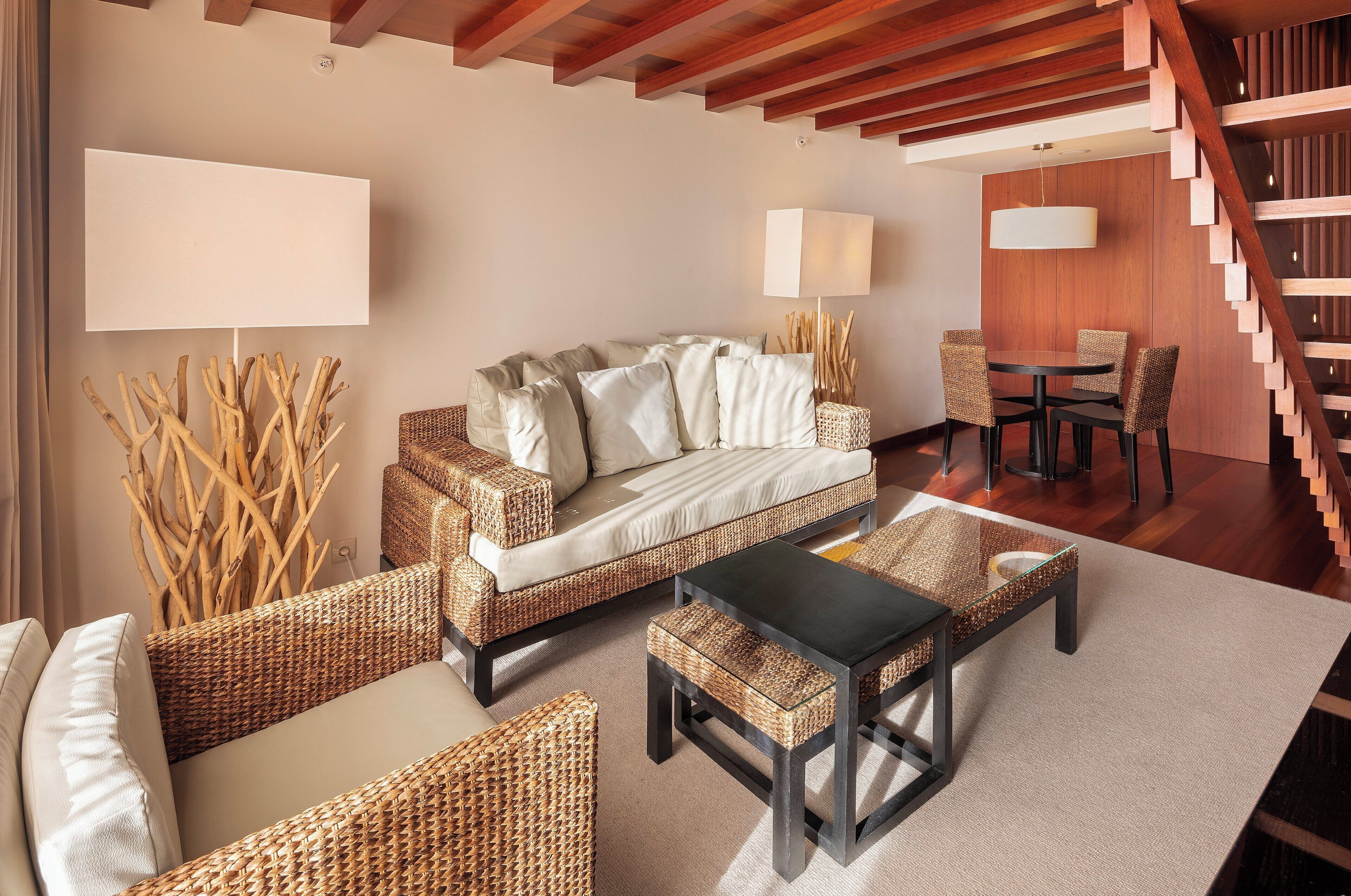 A modern living room with a sofa, chairs, a coffee table, and a staircase.