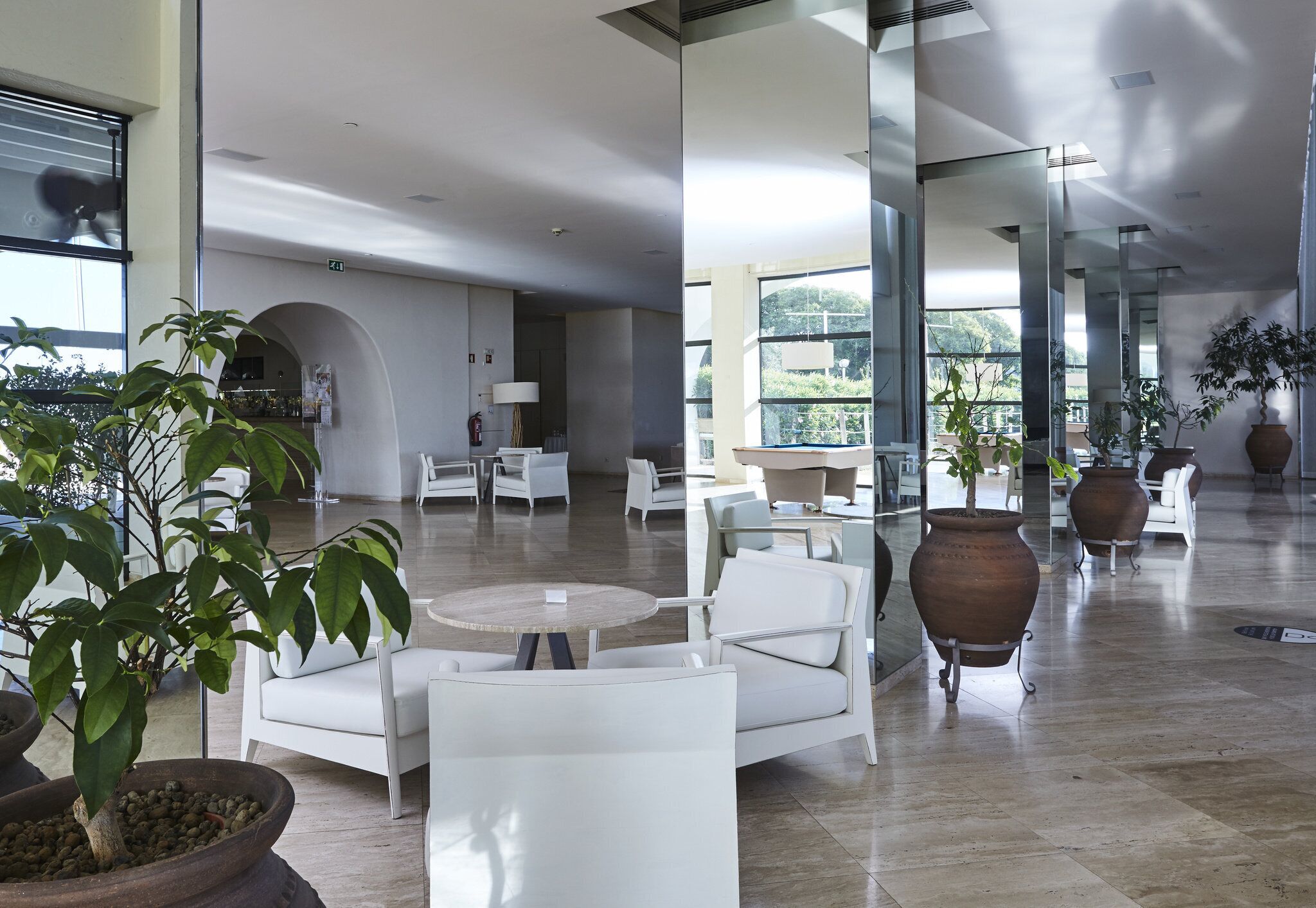 A spacious lobby with modern furniture, large windows, and indoor plants.