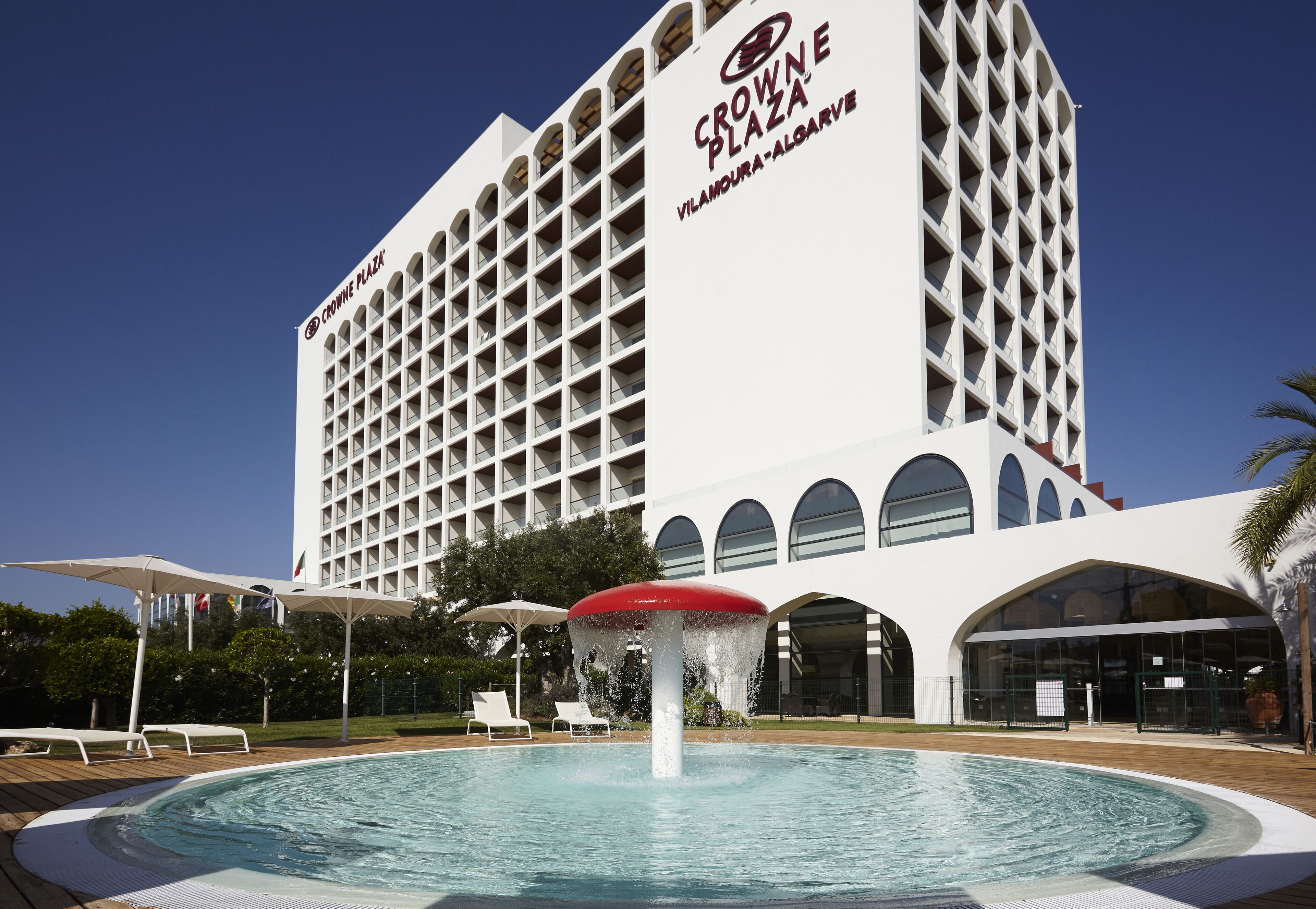 Ett hotell med en stor pool, en fontän och en skylt med texten ”Crowne Plaza Vilamoura-Algarve”.