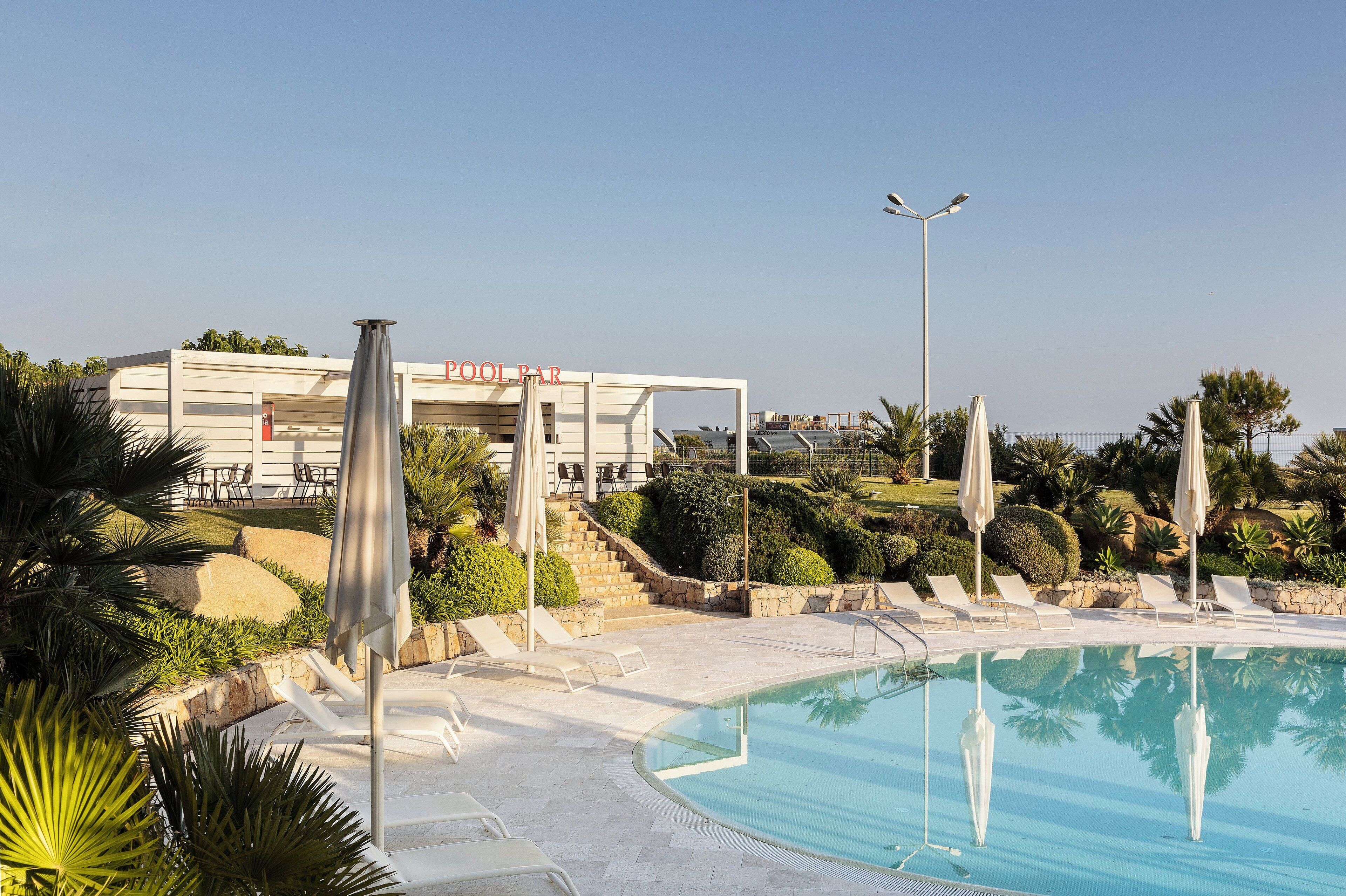 A pool area with lounge chairs, a pool, and a building labeled "POOL PAR".