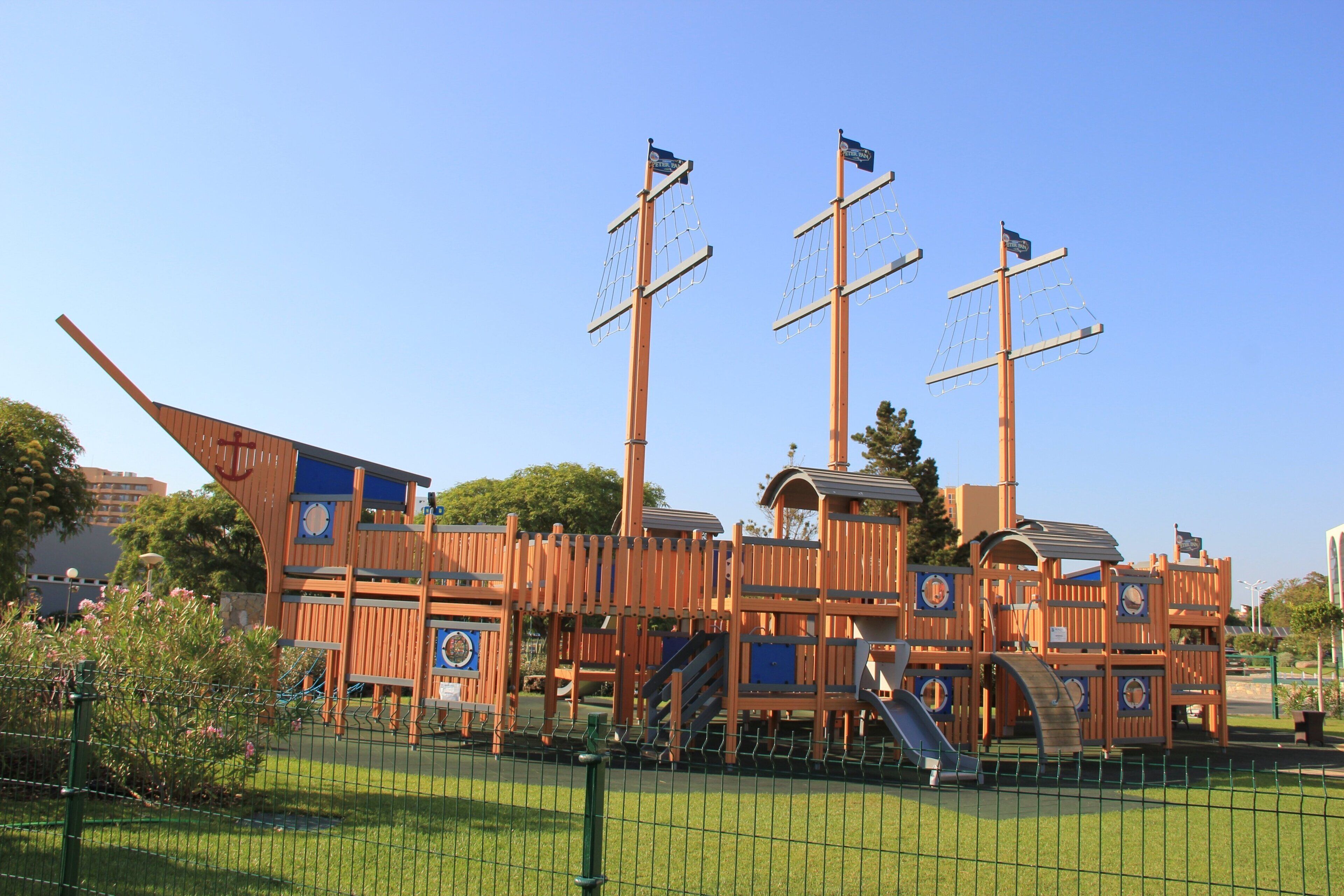 Une structure de jeu en bois sur le thème des pirates, avec plusieurs niveaux et des toboggans.