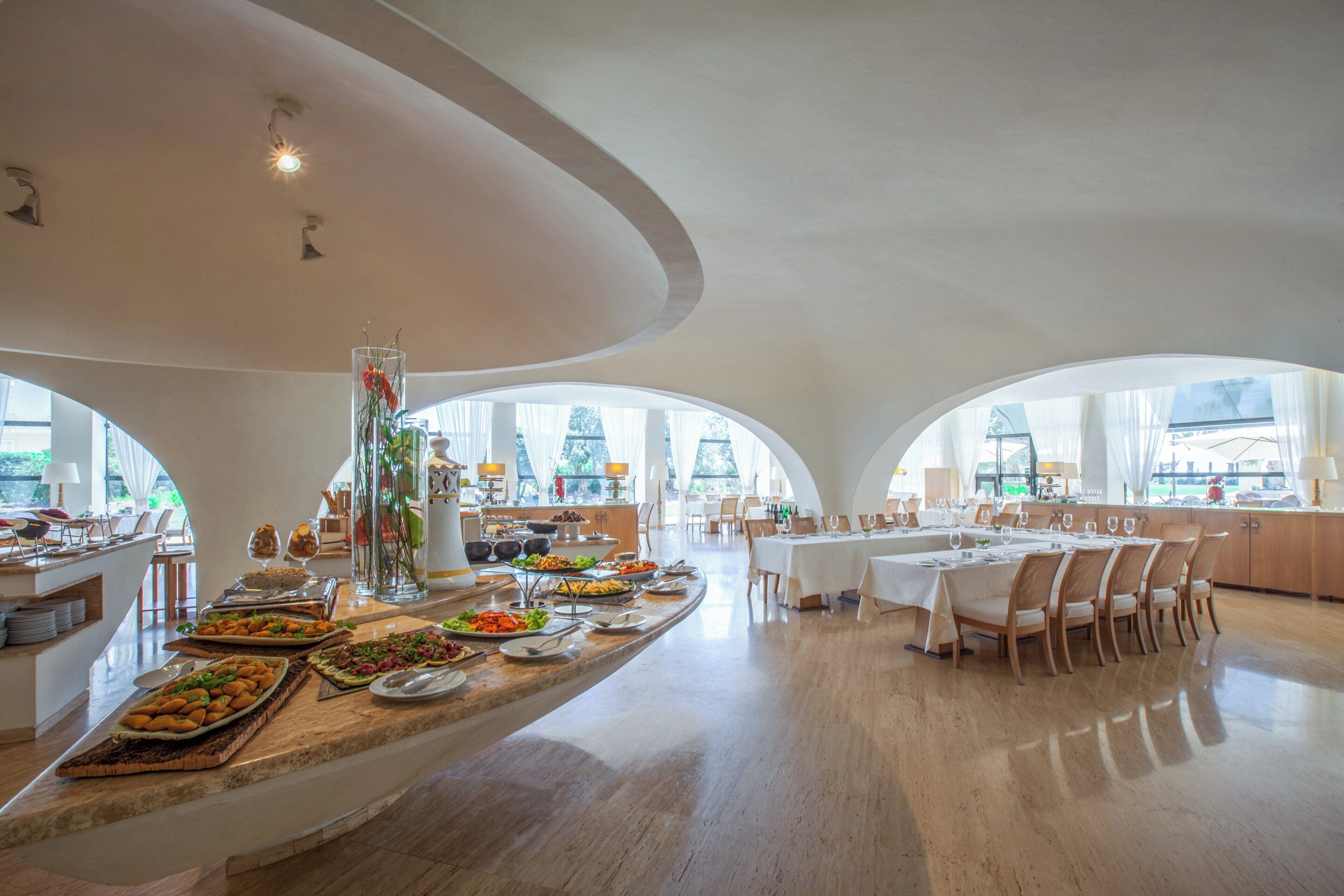 Un comedor amplio con una isla central, varias mesas y vistas al exterior a través de grandes ventanales.
