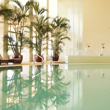 An indoor swimming pool with a wall featuring the text 'almond tree WELLNESS SPA' and a logo.