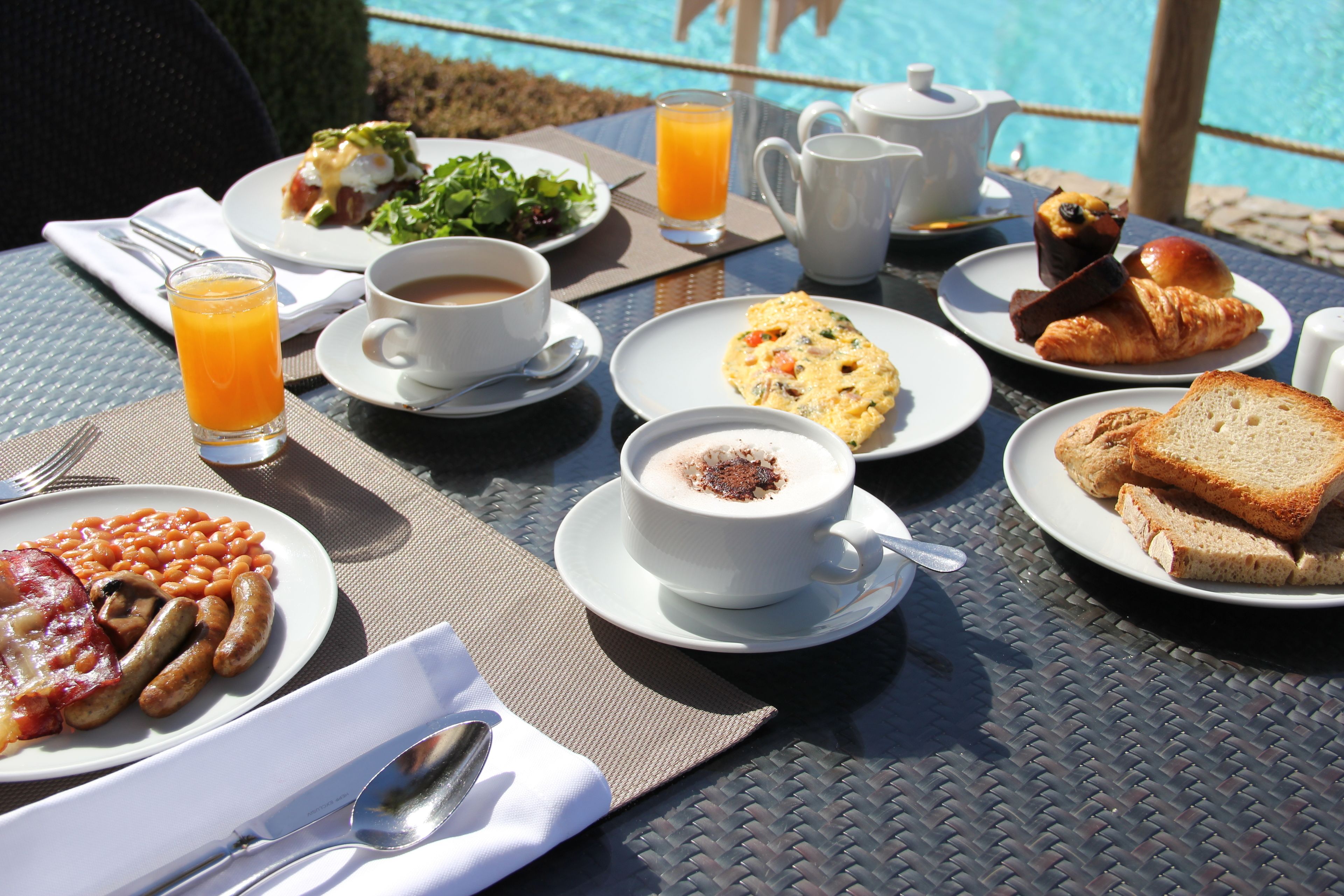 A breakfast table with plates of food, a coffee cup, and a jug of orange juice.