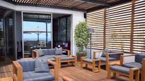 A modern outdoor seating area with wooden furniture and a view of the city. - Madeira Regency Cliff (Funchal)