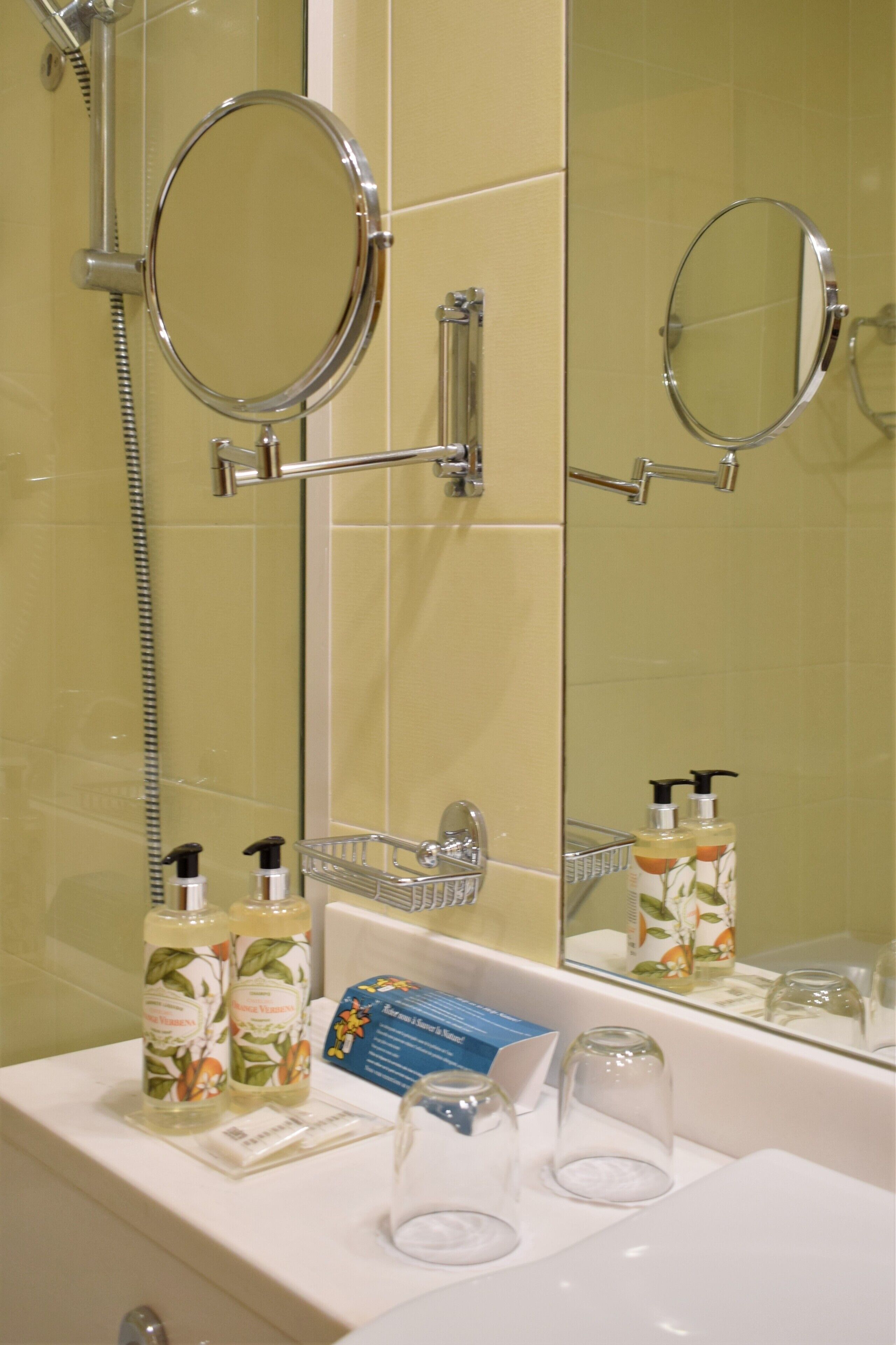 Een badkamer met een douche, een spiegel en toiletartikelen op de wastafel.