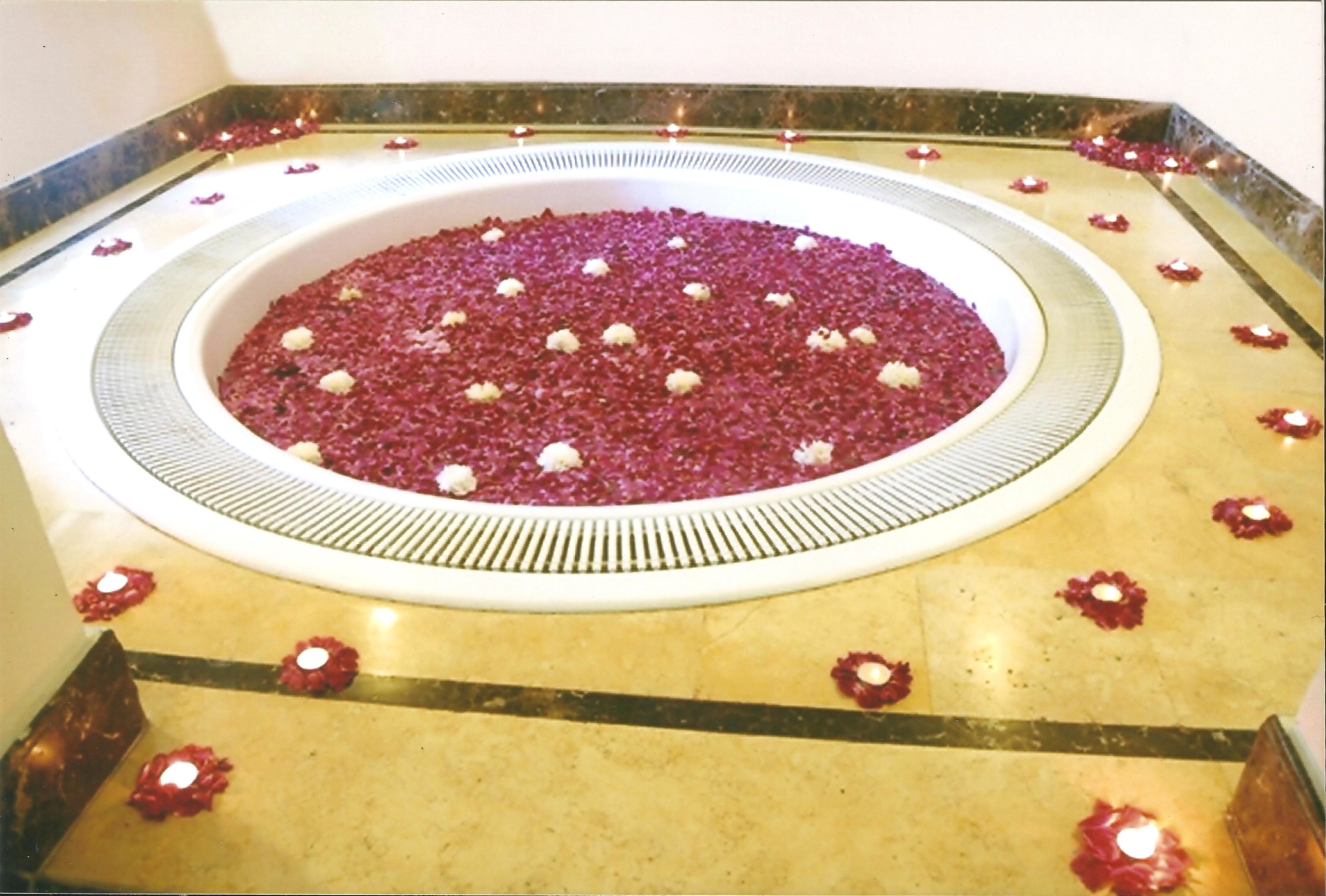 A circular area with a patterned floor, surrounded by red flower petals and candles.