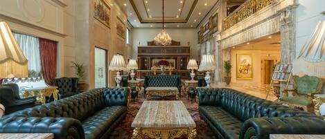 A luxurious lobby with a grand chandelier, plush seating, and ornate decor.