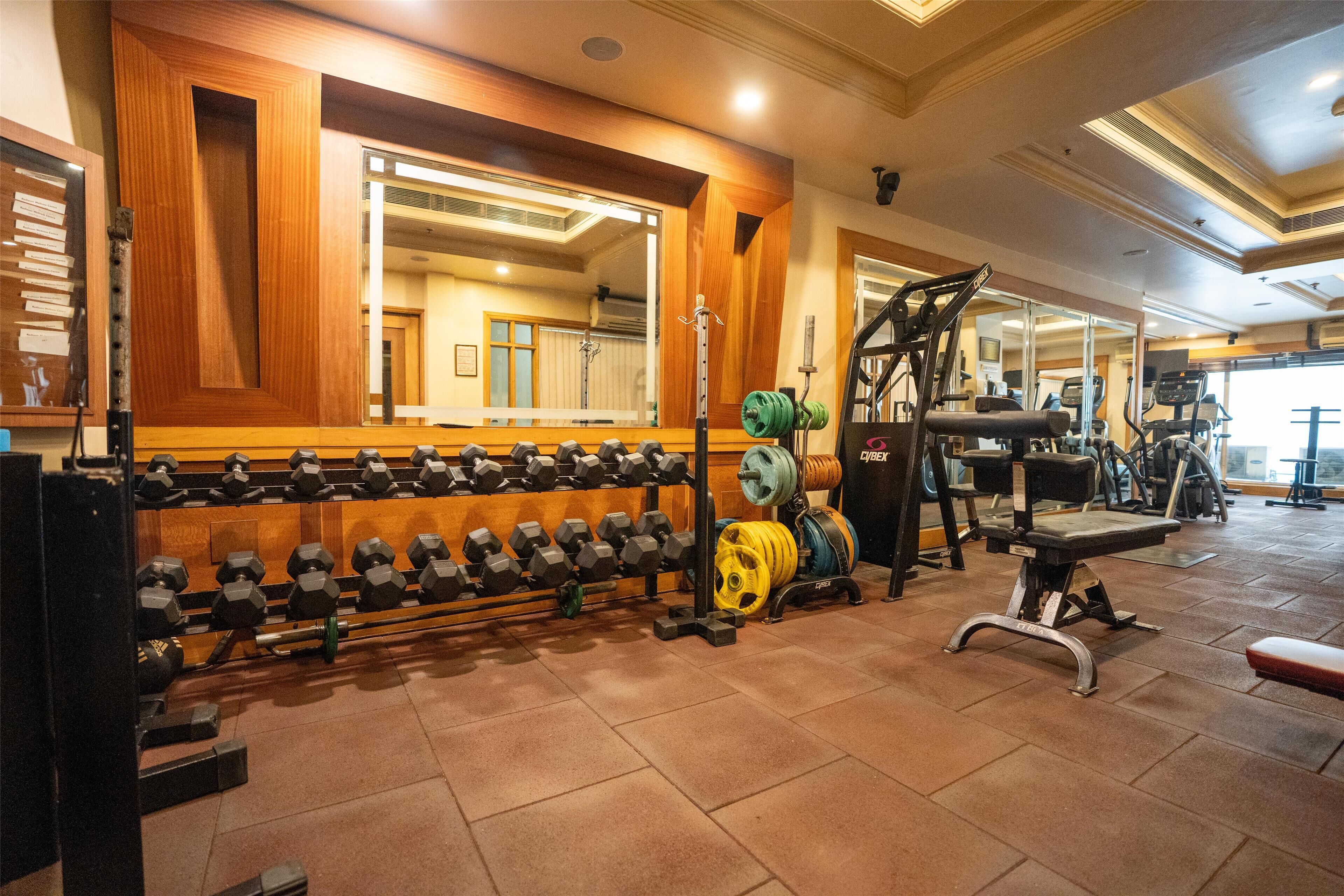 A gym with weightlifting equipment, mirrors, and exercise machines.