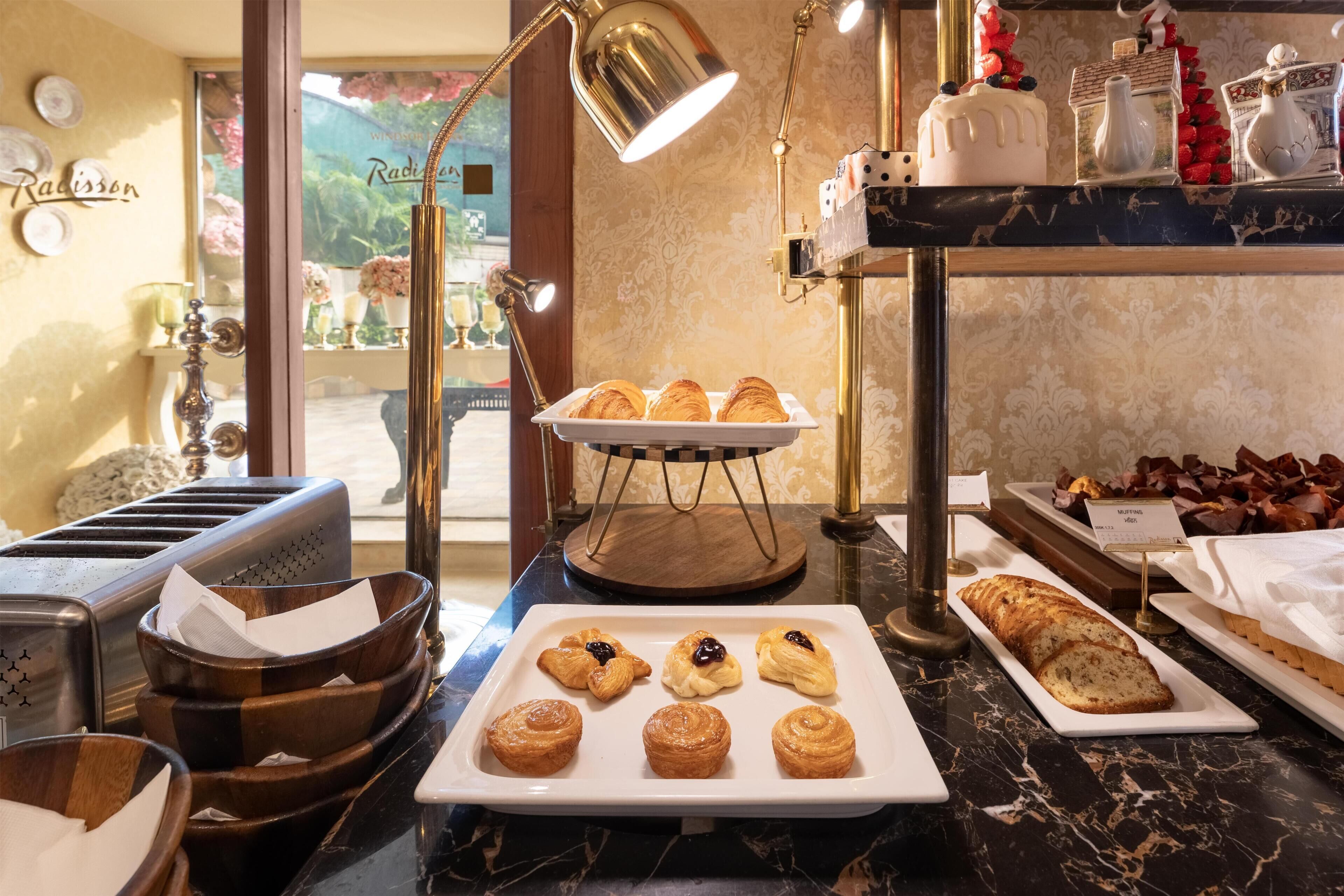 A breakfast buffet with pastries, muffins, and bread.