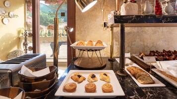 A breakfast buffet with pastries, muffins, and bread.