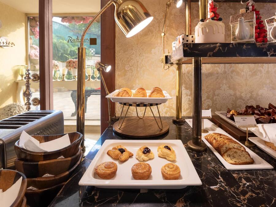 A breakfast buffet with pastries, muffins, and bread.