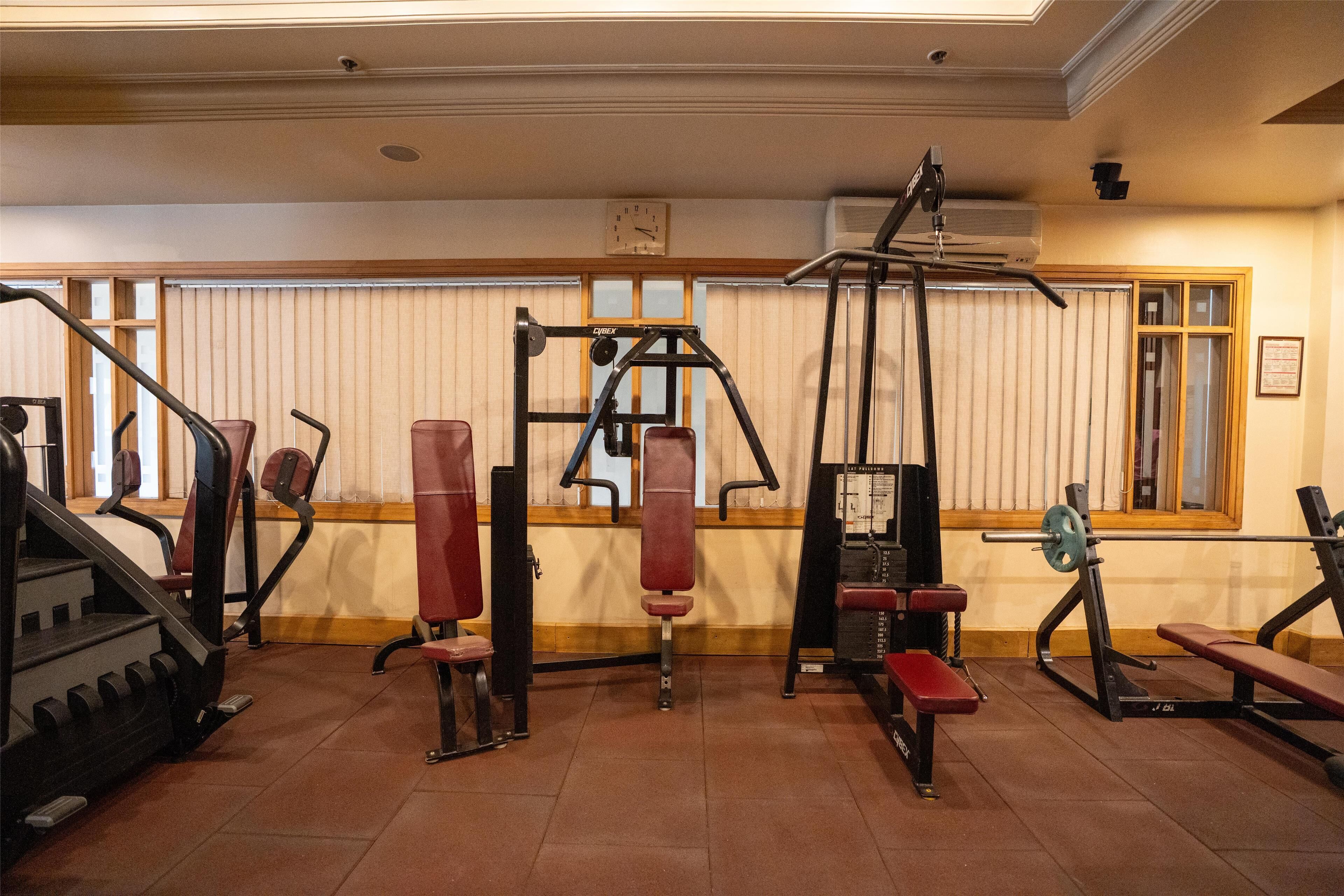 A gym with various exercise equipment, including a treadmill, weight machines, and benches.