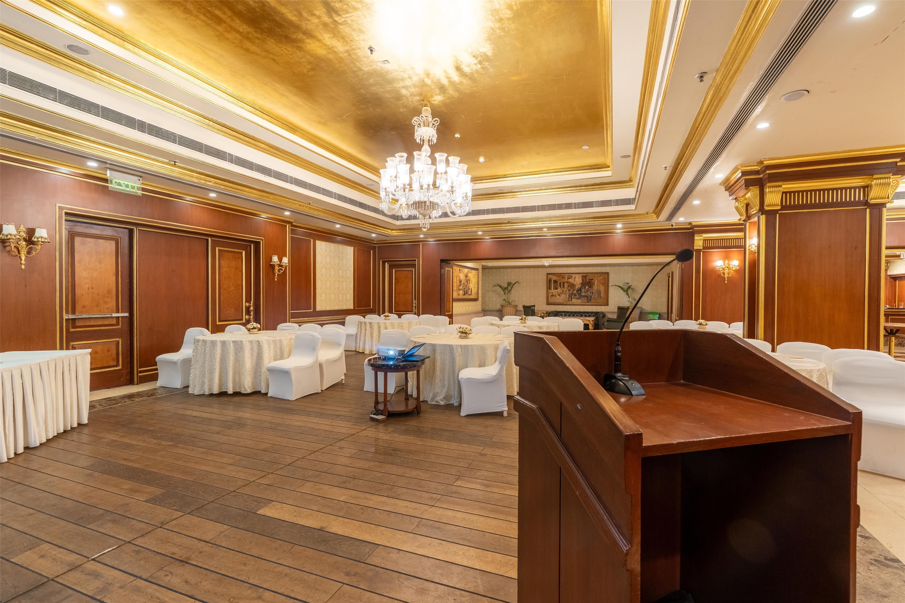 A banquet hall with round tables, white chairs, and a podium.