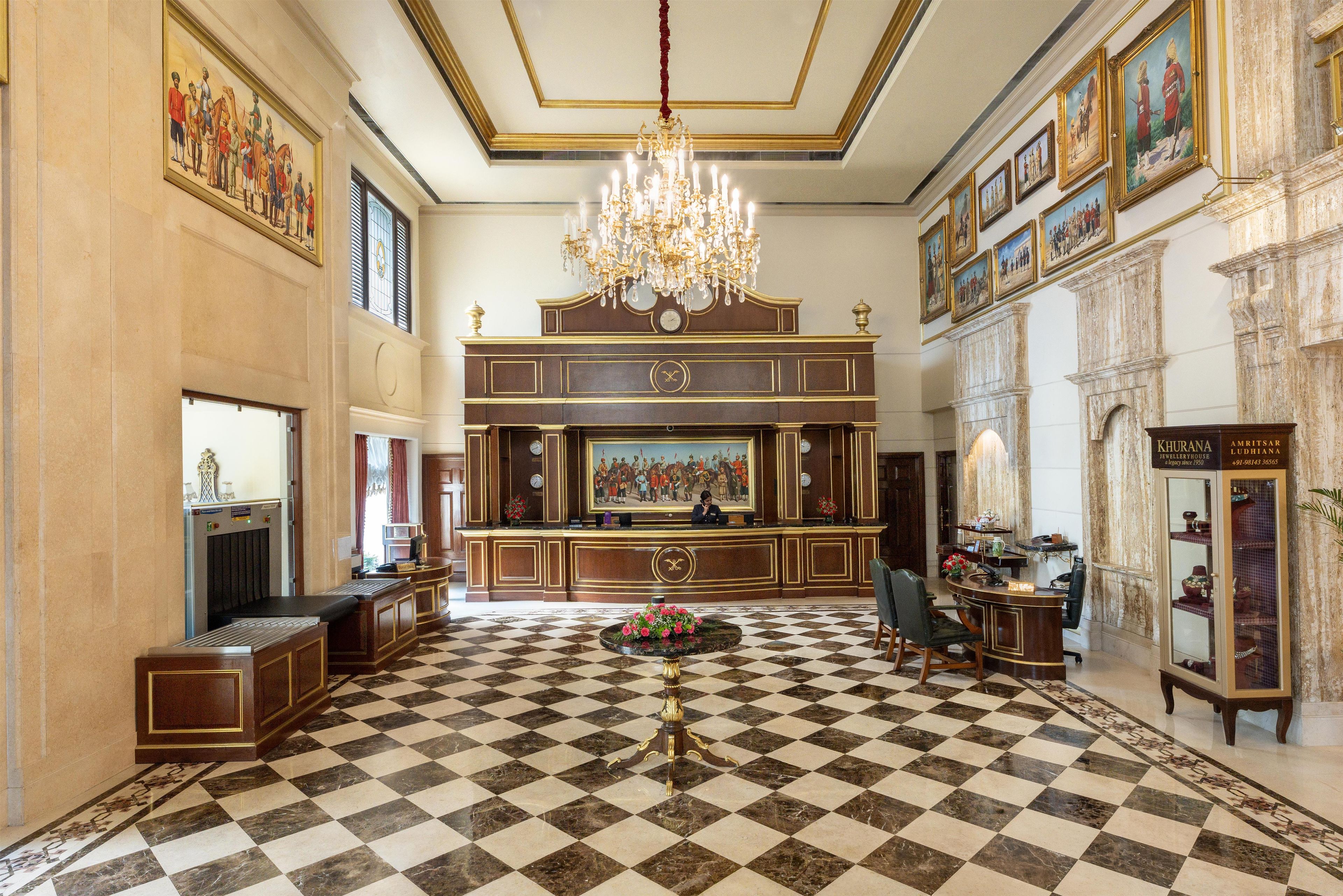 Un lobby imponente con suelo a cuadros, un candelabro y un mostrador de recepción.