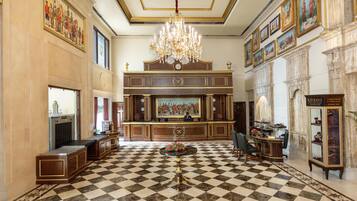 Un lobby imponente con suelo a cuadros, un candelabro y un mostrador de recepción.