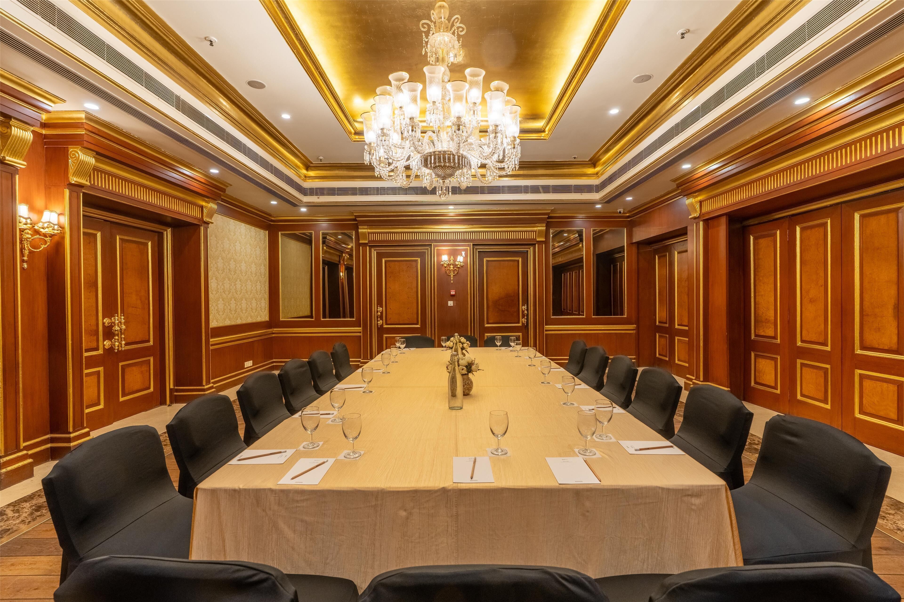A conference room with a long table, black chairs, and a chandelier.